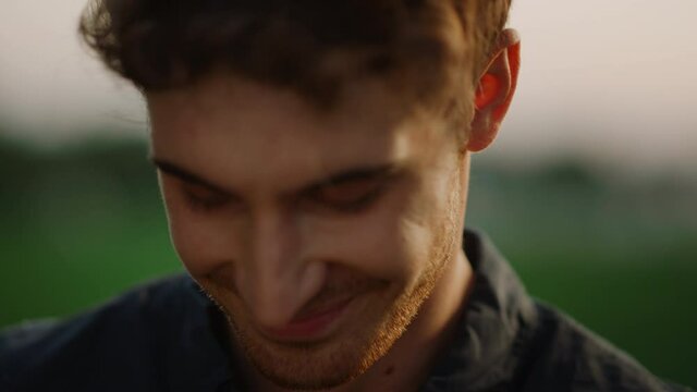 Handsome man looking at camera outdoors at sunset. Cheerful model guy