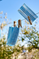 Fototapeta na wymiar Sunlit face masks are hung to dry for disinfection fastened by wooden clothespins. New normal concept