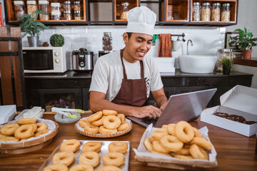 a chef uses a laptop to sell homemade donuts, made in his home kitchen
