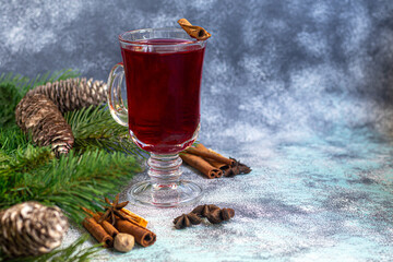 Mulled wine, a warming drink in a cup with spices. Christmas toys. New Year mood. On a light background.