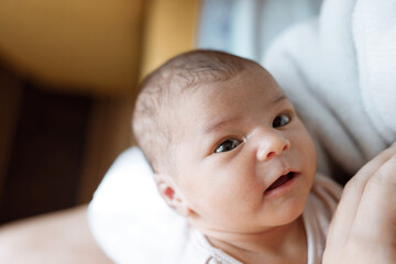 Loving mom carying of her newborn baby at home over window lighting. Woman holds and hugs her child.