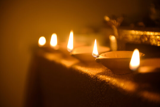 Row of illuminated diyas. Diwali tera cotta earthen lamps shot in perspective. Selective focus lens blur effect.