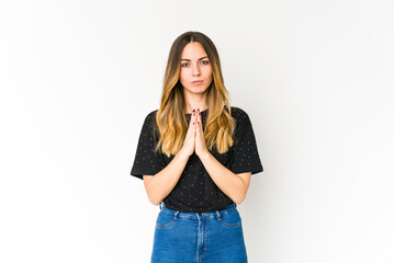 Fototapeta premium Young caucasian woman isolated on white background praying, showing devotion, religious person looking for divine inspiration.