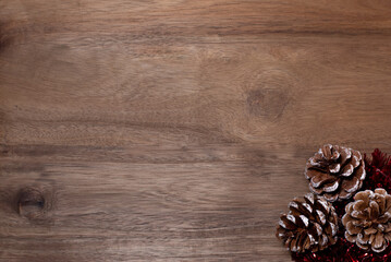 Pine cones with red tinsel on the wooden background.
