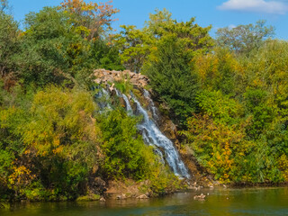 Fototapeta na wymiar beautiful waterfall rushing from mount slope to an emerald lake