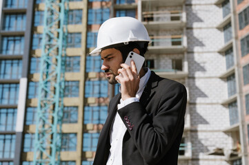 Man in a suit and protective helmet talking on the phone