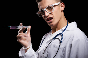 Doctor with liquid in a syringe on a black background and a stethoscope around his neck cropped view