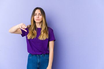 Fototapeta na wymiar Young caucasian woman isolated on purple background showing a dislike gesture, thumbs down. Disagreement concept.