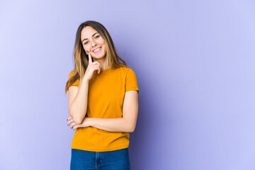 Young caucasian woman isolated on purple background smiling happy and confident, touching chin with hand.