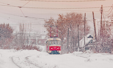 Naklejka premium Red nostalgic tram rides through the winter. Tram and tramlines in Russia at winter with snow
