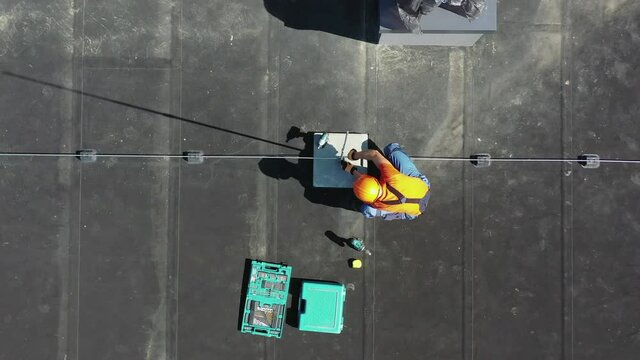 Building Roof Storm Lightning Protection System Design. Caucasian Worker Attaching Tall Metal Rod to the System.