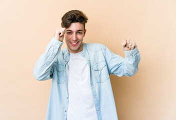 Young caucasian man isolated on beige background dancing and having fun.