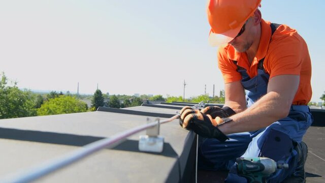 Technician Adjusting Metal Rod of Lightning Protection System on the Top of the Building. Securing Building From Weather Elements.