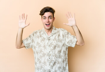 Young caucasian man isolated on beige background receiving a pleasant surprise, excited and raising hands.