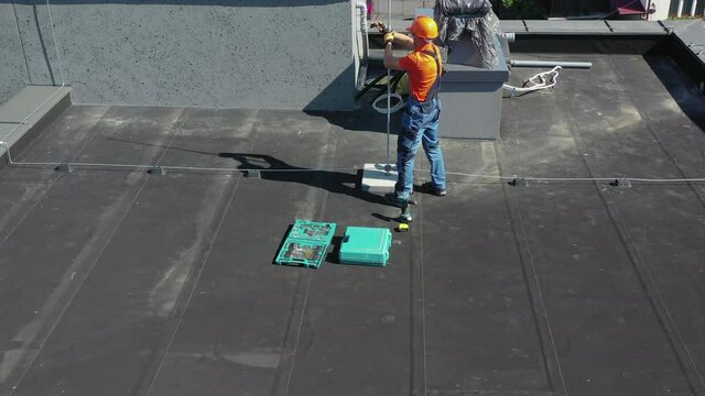 Aerial View of Technician Assembling Metal Rod Lightning Protection Element on the Roof.