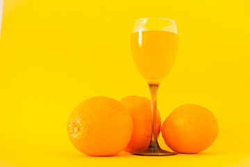 Bright oranges and a glass of orange juice on a bright yellow background. Healthy lifestyle concept. Vitamins and vigor.