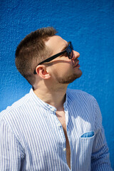 Young guy businessman in a blue shirt and black glasses on a blue background