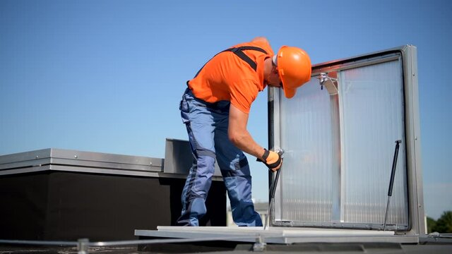Caucasian Worker in His 40s Assembling Roof Entrance on Building Roof