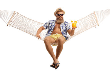 Young bearded man with hat and sunglasses sitting on a hammock swing with a cocktail