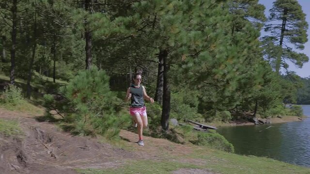 Mujer joven de trail running corriendo en la monta&ntilde;a al aire libre, haciendo entrenamiento de resistencia. Estilo de vida saludable y disciplina deportiva