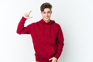 Young caucasian man isolated on white background holding something little with forefingers, smiling and confident.