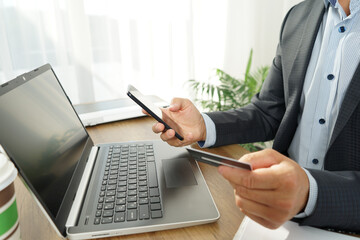male businessman makes online purchases using a credit card, laptop and smartphone