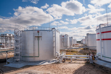 Obraz premium Cloudy day. Tanks with oil for further transportation of oil through pipes at an oil refinery and oil pumping station
