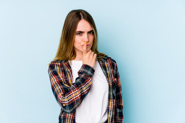 Young caucasian woman isolated on blue background thinking and looking up, being reflective, contemplating, having a fantasy.