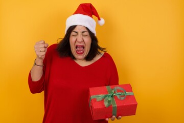 Caucasian brunette woman rejoicing her success and victory clenching her fists with joy. Lucky woman being happy to achieve her aim and goals. Positive emotions, feelings.