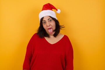 Beautiful caucasian woman with happy and funny face smiling and showing tongue. Wearing casual clothes and standing against white studio background.