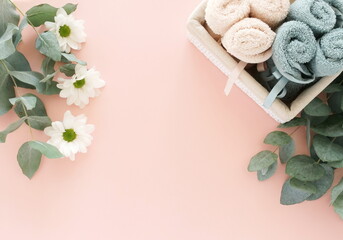 Fototapeta na wymiar Bath products towels, eucalyptus leaves, flowers on pink backdrop top view.Beauty, wellness, body care concept. Spa background. copy space
