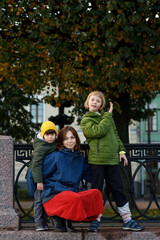 Family on a walk along the city's waterfront. Mom, daughter and son look at the camera and smile.