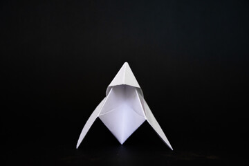 triangle of paper, elegant white origami on a black background