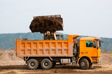 Wheel loader loads clay into the bucket of a dump truck