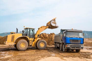 Wheel loader loads clay into the bucket of a dump truck