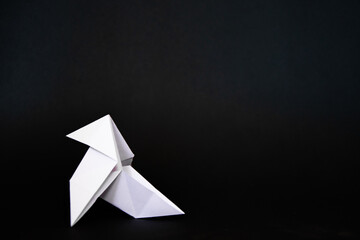 White paper bow pie origami figure  in the left of a black background
