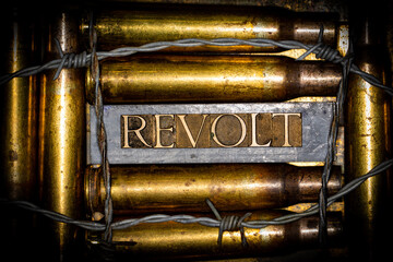 Naklejka premium Revolt text message on lead bars between copper 50 caliber gun casings on vintage textured grunge copper and gold background lined with barbed wire