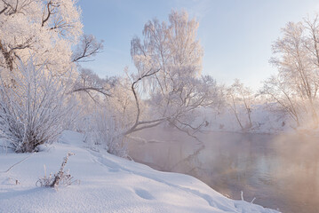 Christmas Landscape with a floating river surrounded by frozen trees. Frosty morning in the winter forest.