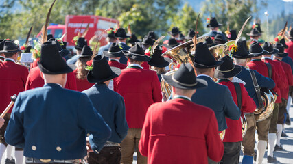 Gemischte traditionelle Dorfmusikkapelle marschiert gemeinsam eine Stra&szlig;e entlang zu einem Volksfest