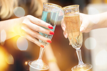 Two women's hands with glasses of champagne on a festive background.