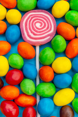 Lollipop on stick between colorful dragee. Close up.