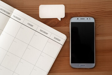 Mobile phone, blank calendar and speech bubble notes. Wood table. Top view.