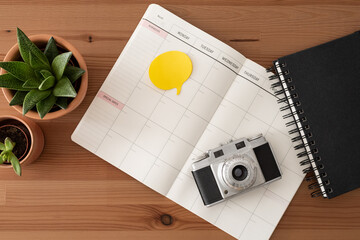Vintage camera, black notebook, blank diary, yellow notes and cactus. Wood table. Top view.