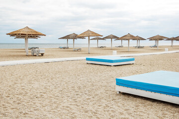 Beautiful beach on the seashore. Lots of sun umbrellas. Sun loungers on the beach. Beach chairs and large umbrellas. Clean beach without people. Summer vacation at the sea.