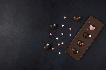 Dark chocolate bar with decorations isolated on a dark background. Top view, flat lay. Free space for text.