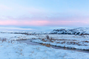 Fototapeta na wymiar River on the plain in Iceland. The banks are covered with snow. Winter landscape, open spaces.