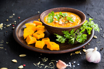 Delicious healthy pumpkin soup, herbs, and ingredients for the dish. Creative atmospheric decoration