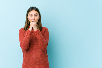 Young caucasian woman praying for luck, amazed and opening mouth looking to front.