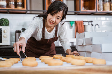 beautiful women wearing aprons while preparing donuts with tongs of food to decorate on the table...