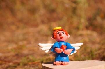 Figure of an angel made of plasticine on a colored background.